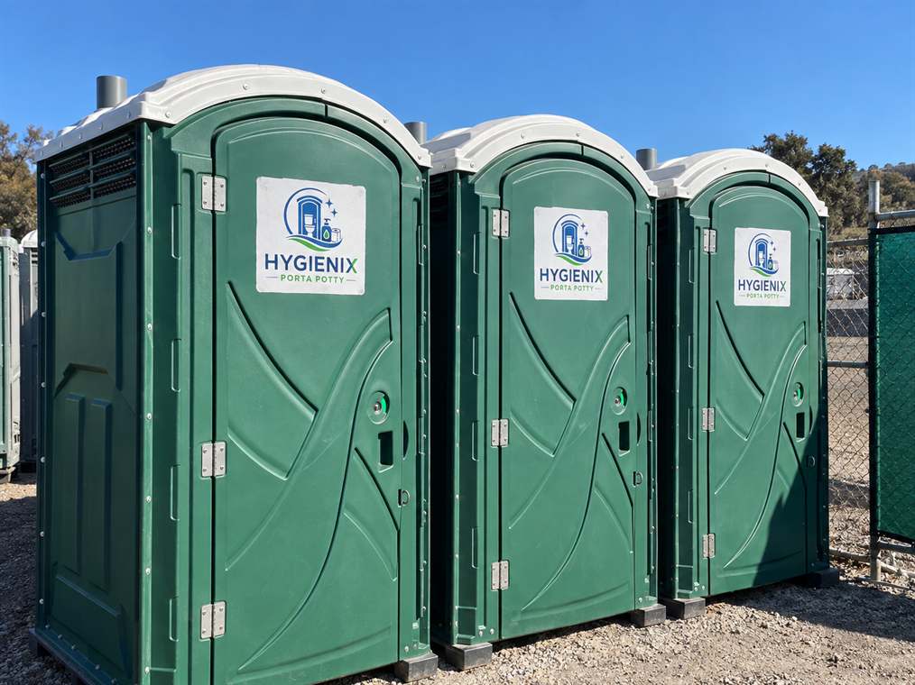 Three green Hygienix Porta Potty units angled in a storage yard