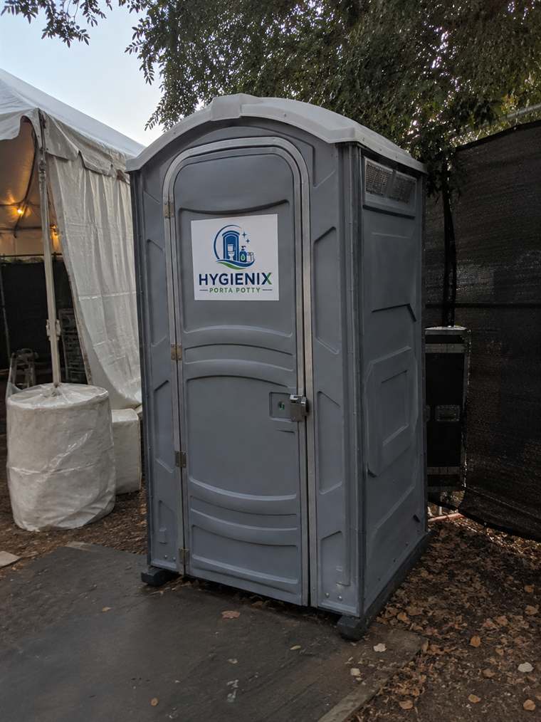 Single grey Hygienix Porta Potty unit beside a marquee tent