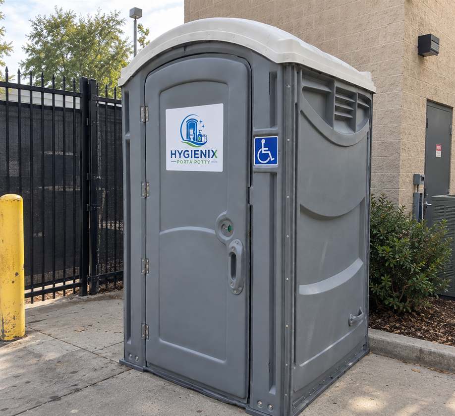 Hygienix Porta Potty ADA unit beside parking lot fence